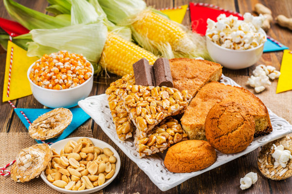 Diferentes tipos de comidas de Festa Junina dispostos sobre uma mesa de madeira.