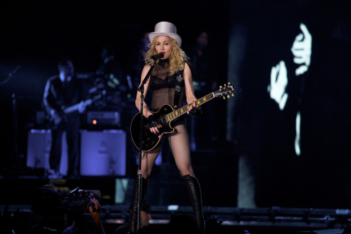 Madonna usando chapéu e roupa preta transparente durante show.