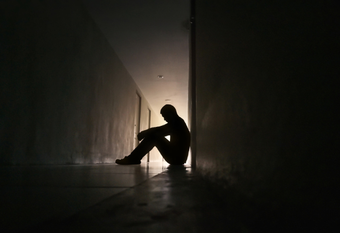 Pessoa sentada em lugar escuro em alusão à depressão, uma das condições que podem ser tratadas com cetamina.
