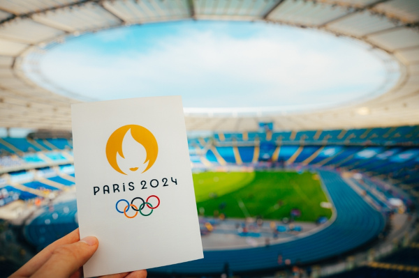 Pessoa segurando um cartão que faz alusão às Olimpíadas de Paris 2024.