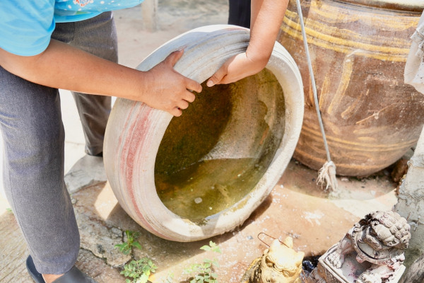 Mulher tirando a água parada de um pneu, uma das principais medidas de prevenção da febre do oropouche.