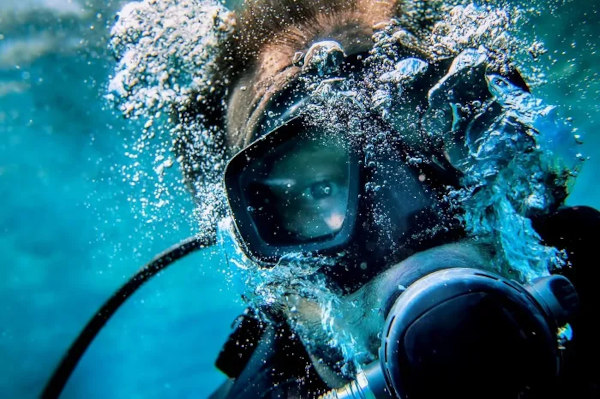 Mergulhador com máscara de mergulho, uma alusão ao questionamento sobre por que não enxergamos bem debaixo d’água.