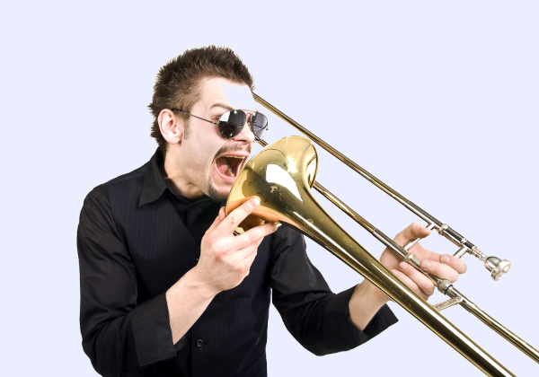 : Homem com a boca aberta no trombone, uma alusão a “botar a boca no trombone”, uma das expressões idiomáticas mais conhecidas.