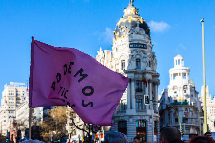 Bandeira do Podemos, partido de extrema-esquerda espanhol, hasteada em frente a um edifício.