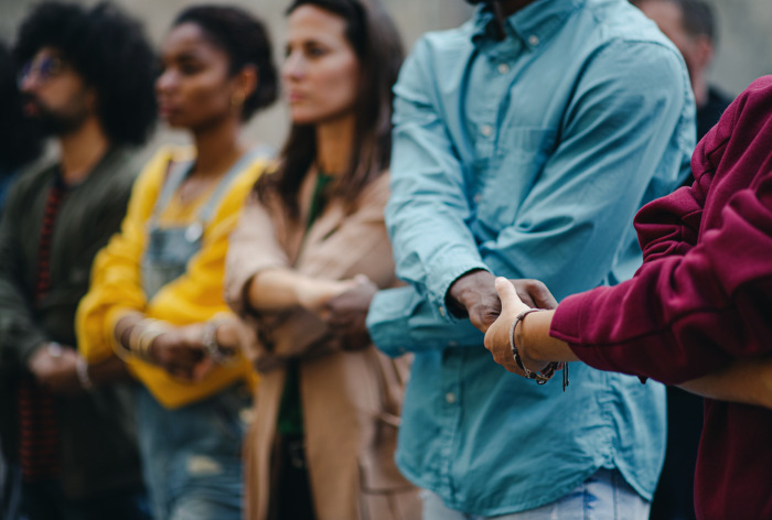 Pessoas de mãos dadas em um protesto, alusão à importância dos movimentos sociais.