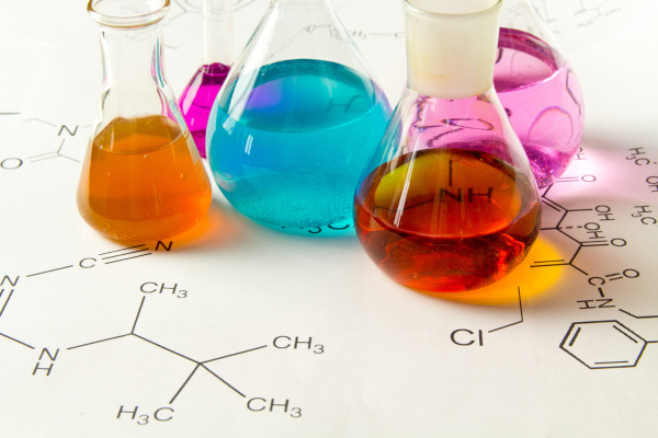 Frascos de laboratório sobre fórmulas químicas de compostos orgânicos.