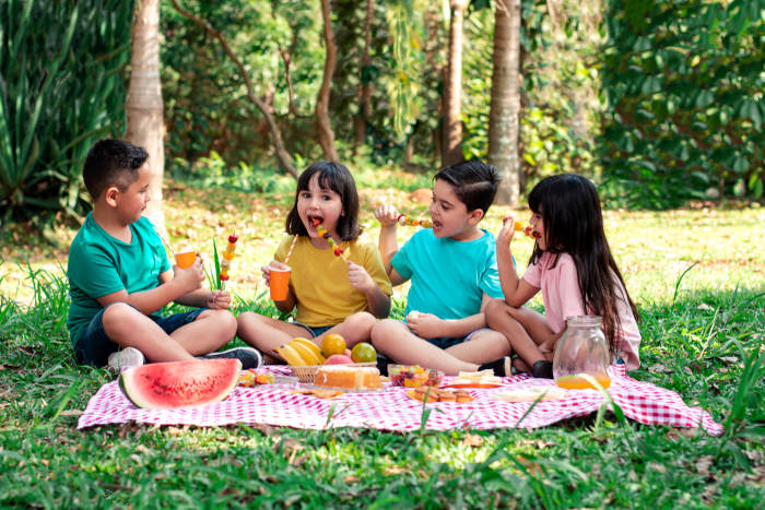 Crianças fazendo piquenique no parque, uma dica para o Dia das Crianças.