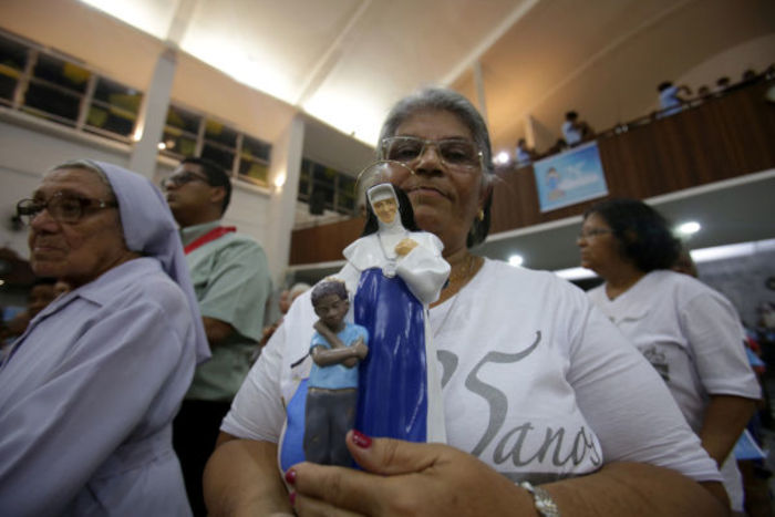 Fiel segurando imagem de Santa Dulce dos Pobres em igreja de Salvador. [3]