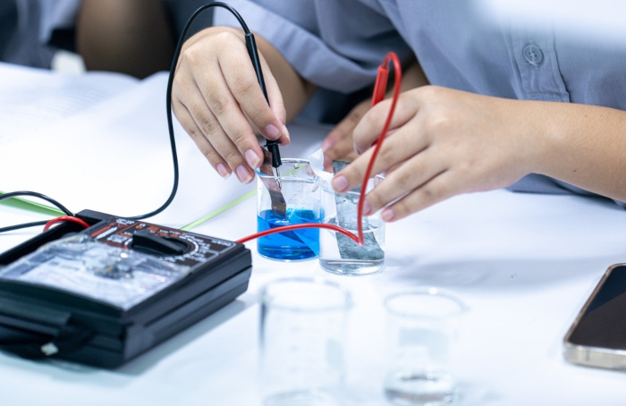 Pessoa manuseando experimento de uma bateria em texto sobre eletroquímica no Enem.