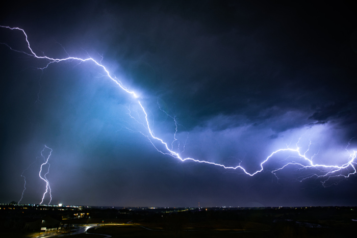Raios no céu noturno de uma cidade, em texto sobre história da eletricidade.