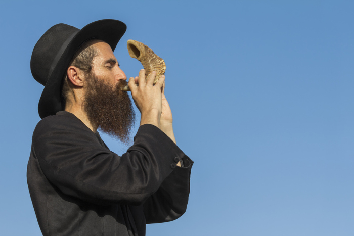 Judeu ortodoxo tocando shofar, ato que encerra o Yom Kippur.