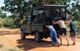 Três homens empurrando um jeep