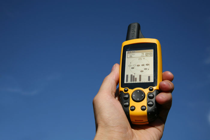Mão segurando GPS, aparelho usado para medir latitude.