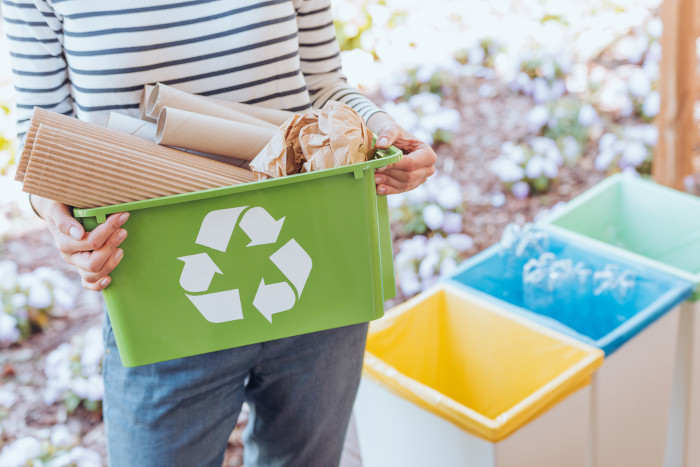 Mulher segurando recipiente com papéis, separados pelo método da catação para reciclagem.