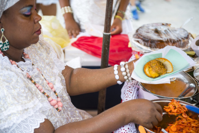 Baiana servindo acarajé em uma banca, um prato típico da cultura brasileira.