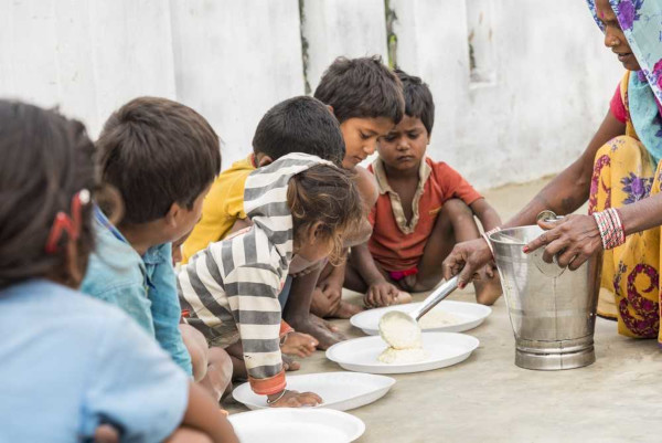 Crianças pobres sendo alimentadas representando uma das preocupações da Teoria Malthusiana.