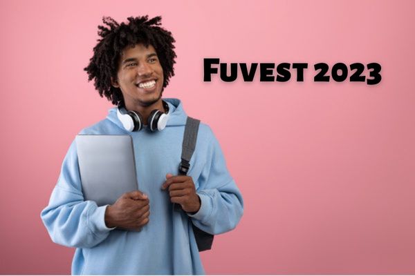 Estudante negro sorrindo com fonte de ouvido no pescoço e blusa de frio azul ao lado do texto Fuvest 2023