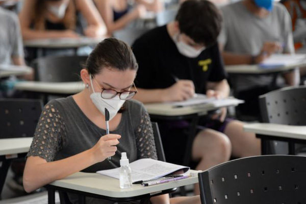 Estudante com máscara branca fazendo prova