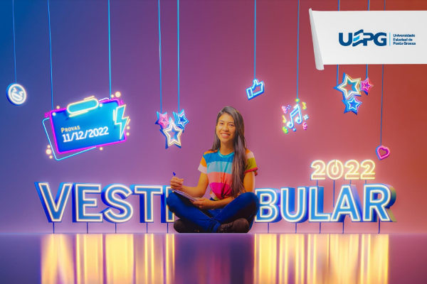 Em imagem de campanha do vestibular, uma jovem mulher sentada com pernas cruzadas e caderno no colo está sorrindo. Texto Vestibular 2022 UEPG