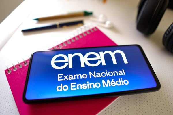Celular com a logo do Enem em cima de uma agenda na cor rosa
