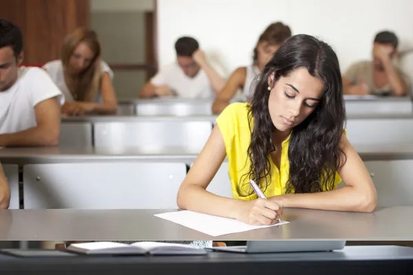 Estudante em sala de aula escrevendo